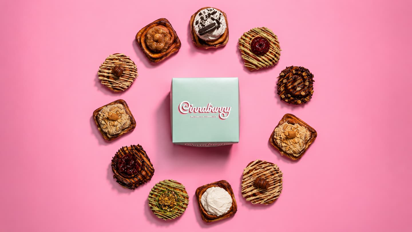Cimet rolnice poređane u krug oko mentol Cinnabunny kutije, na roze podlozi